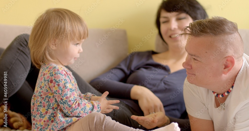 The child plays with his mother, the development of fine motor skills, she takes a small object from her mouth with her hand. In the background, a partner in bokeh smiles.
