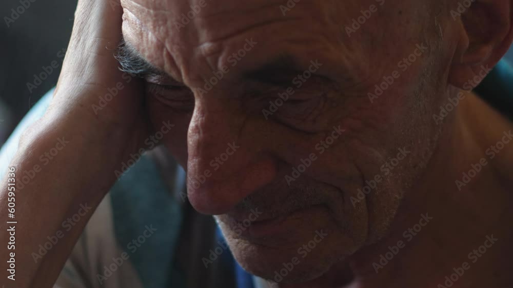 portrait of a sad caucasian old man, holding his head with his hands ...