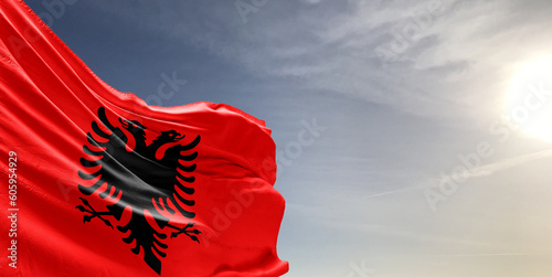 Albania national flag cloth fabric waving on beautiful grey sky Background.