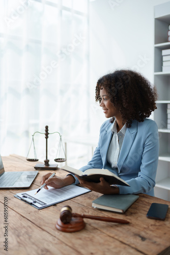 Young African American lawyer studying a case for a client and signing a legal contract to fight her opponent in court. Legal and lawyer concepts. photo