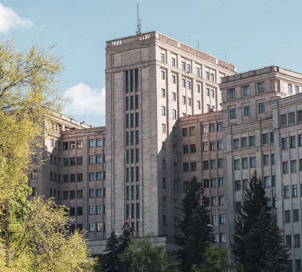 Karazin National University main building facade. Located on Freedom (Svobody) Square with green trees and blue sunny sky. Kharkiv city, Ukraine