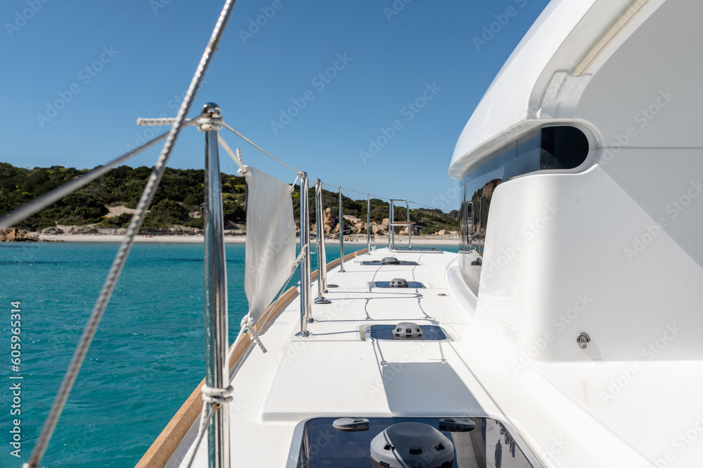 Fototapeta premium Deck of catamaran with metal railing floating in blue sea water on sunny day