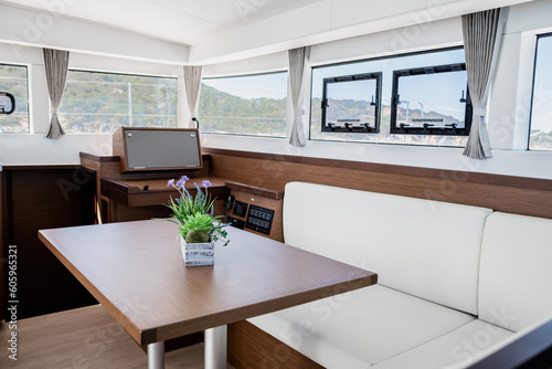 Luxury interior of dining room with sofa and wooden table in cabin of contemporary catamaran