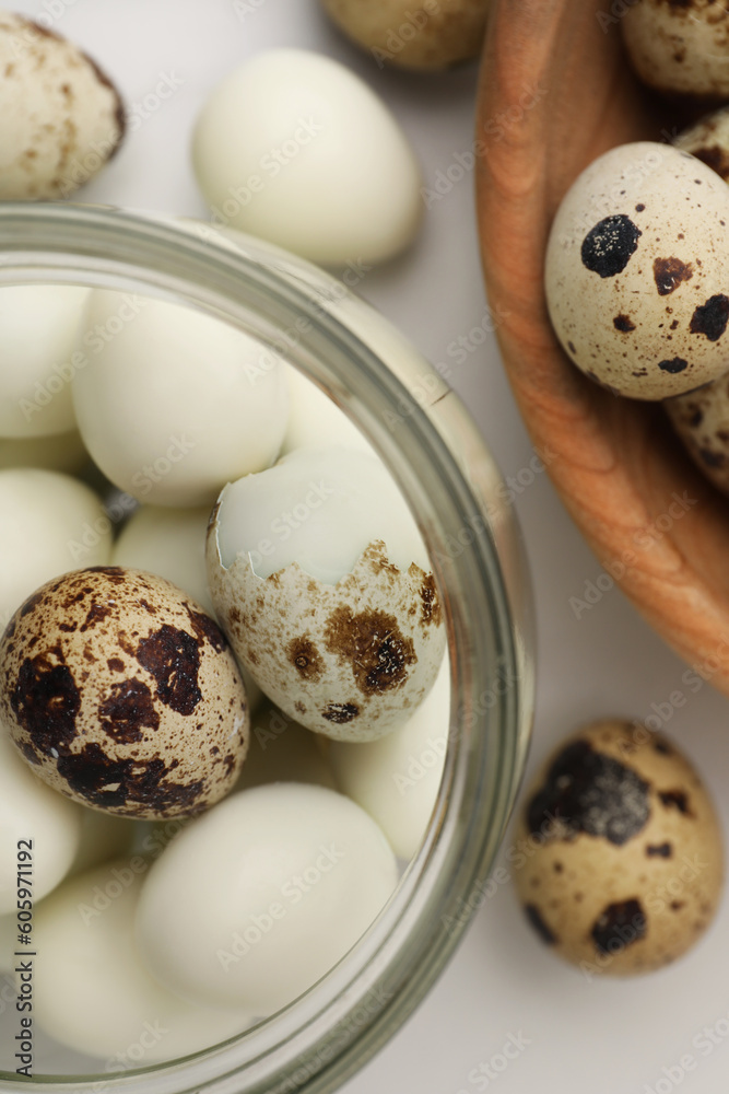 Unpeeled and peeled boiled quail eggs on white table, flat lay Unpeeled and peeled boiled quail eggs on white table, flat lay