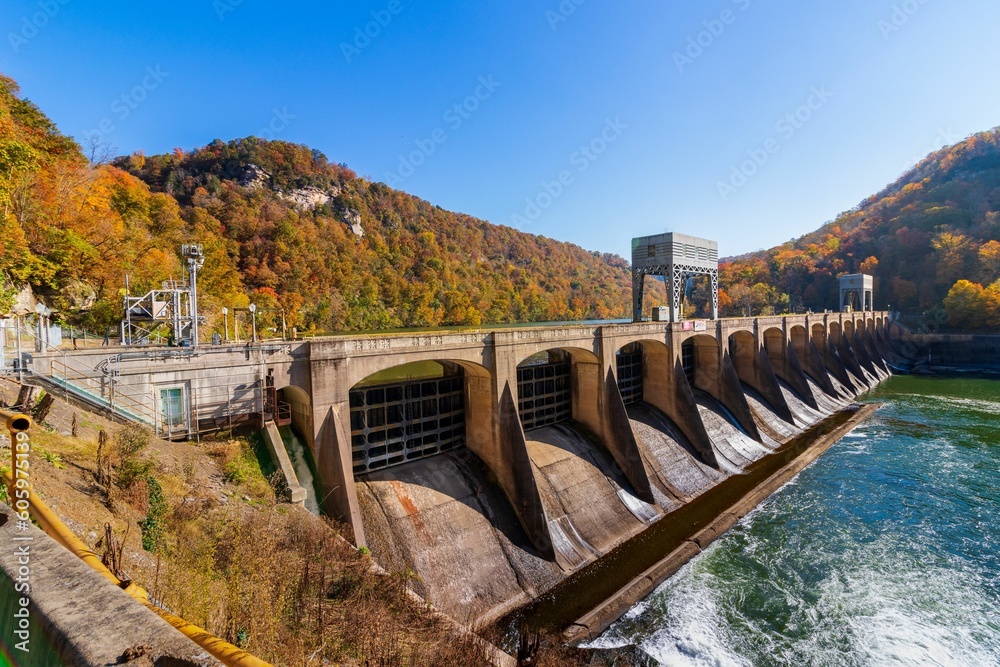 Majestic view of a dam spillway on the side of a mountain, with the tranquil waters of a lake below