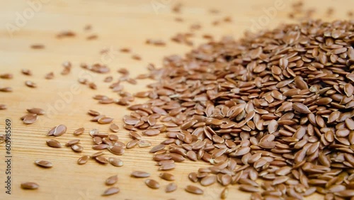 Closeup video of a handful of flaxseed on a wooden surface