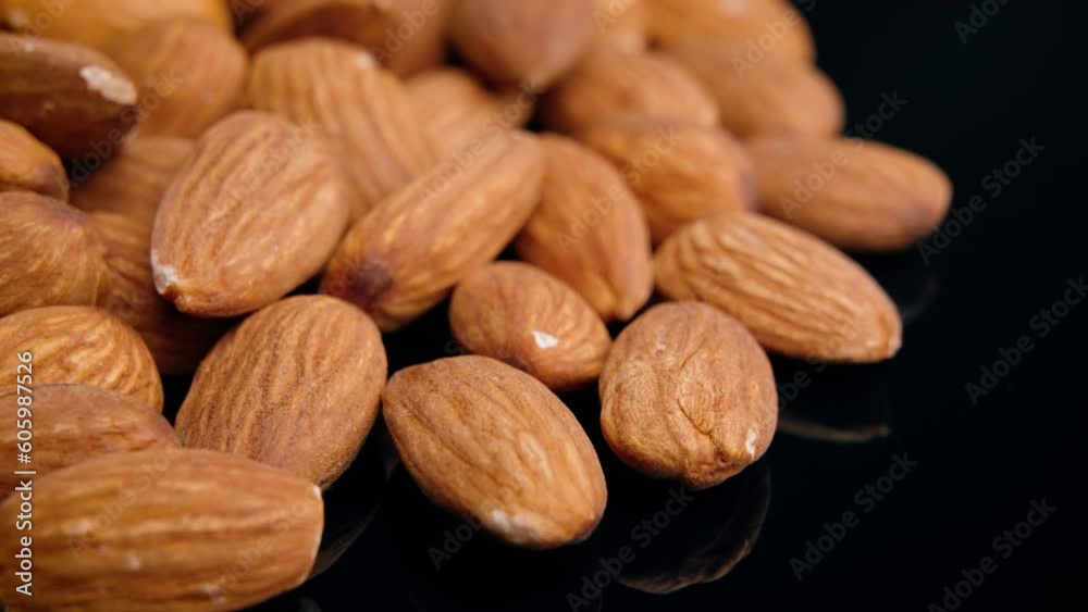 Close-up view of many almonds placed on a black reflecting surface