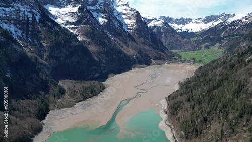 Blue lake surrounded by snow capped mountains. Switzerland. Aerial circular view photo