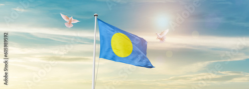 Waving Flag of Palau in Blue Sky. The symbol of the state on wavy cotton fabric.