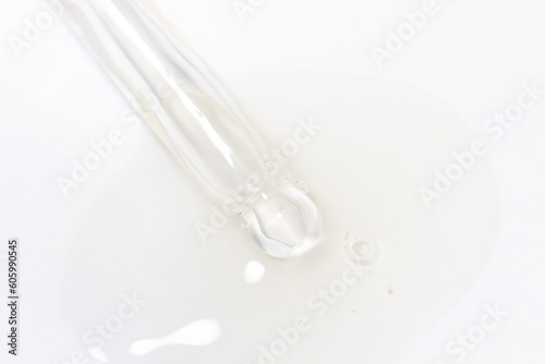 Transparent pipette with gel or liquid flowing out on a light background.