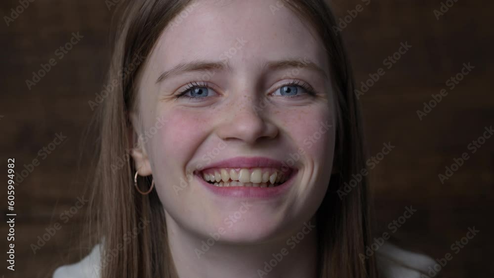 Portrait of a beautiful happy girl with blond hair and freckles looking at the camera and smiling charmingly, close up Portrait of a beautiful happy girl with blond hair and freckles looking at the camera and smiling charmingly, close up