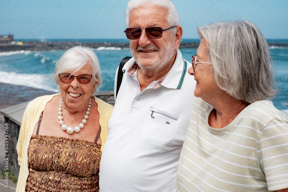 Smiling group of senior people in sea vacation enjoying travel and sunny day close to the beach. Retirement lifestyle concept
