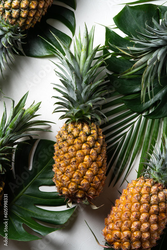 Fresh pineapple with tropical leaves on white background.