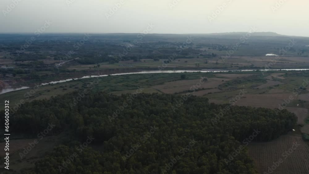 Ariel view of river and green hills near Islamabad, Pakistan with gloomy sky on the horizon