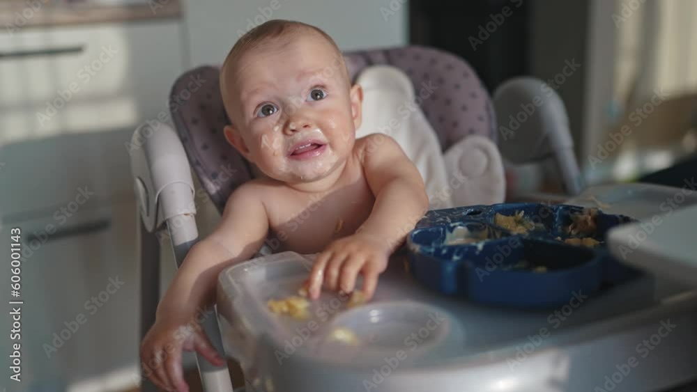 baby dirty eats. happy family a child toddler concept. baby dirty sitting messing with food at the table for feeding in the kitchen lifestyle. grimy toddler in the kitchen baby dirty eats. happy family a child toddler concept. baby dirty sitting messing with food at the table for feeding in the kitchen lifestyle. grimy toddler in the kitchen