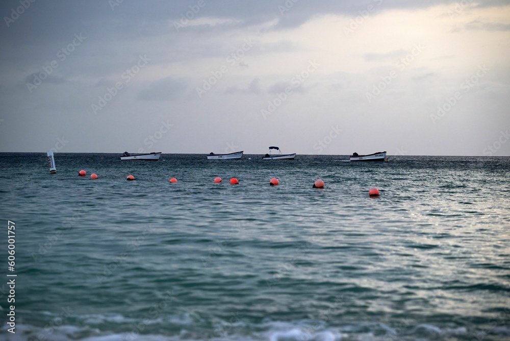 View of the sea with boats and red buoys at sunset.