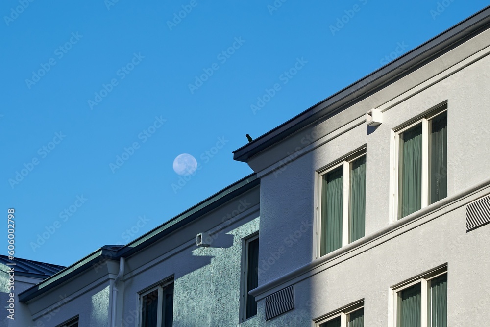 Scenic shot of a modern building against the blue evening sky with the moon Scenic shot of a modern building against the blue evening sky with the moon