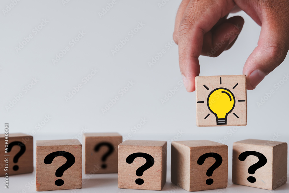 Hand Choosing wooden cube with light bulb icon among wooden cubes with question mark icon over white background use for Creative idea,Innovation,New idea,Creative thinking,business concept. Hand Choosing wooden cube with light bulb icon among wooden cubes with question mark icon over white background use for Creative idea,Innovation,New idea,Creative thinking,business concept.