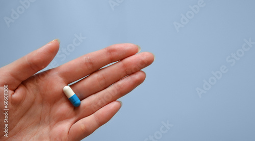 capsule on the palm of your hand on a blue background  medication  day of a medical worker  medical care  banner for the hospital