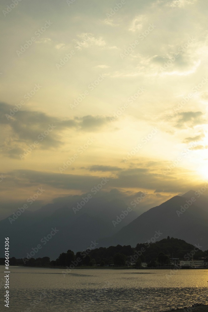 Landscape of sunset hazy sky over lake Como and silhouette mountains in Italy, vertical shot