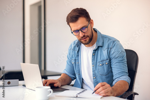 Business man working in office with laptop and documents on his desk.
