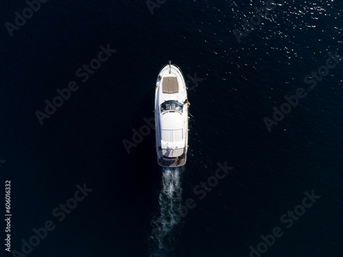 Aerial top view of a boat sailing in the water leaving a trail