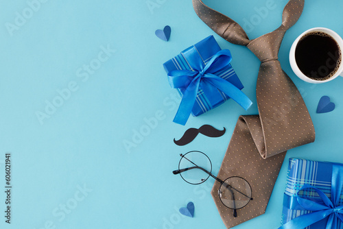 Celebrate Father's Day concept. Top view flat lay of necktie, eyeglasses, gift boxes, mustache, cup of coffee and hearts on light blue background with blank space for text or message
