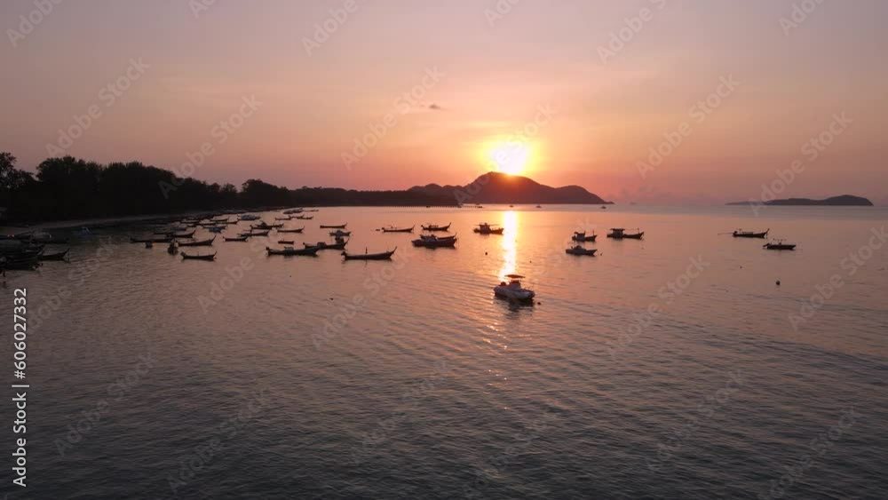 Vibrant and colorful purple sunset with silhouette of mountains Colorful sunset behind mountains of tropical island and beach with boat. motion move pan up topview Vibrant and colorful purple sunset with silhouette of mountains Colorful sunset behind mountains of tropical island and beach with boat. motion move pan up topview