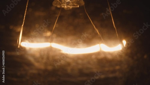 close-up of a tungsten base of a flaring up and fading light bulbs in the darkness. selective focus. power outage, dim light bulb