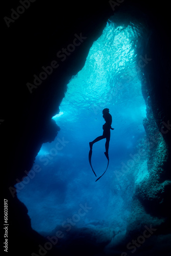 silhouette of free diver woman freediving in cave. photo