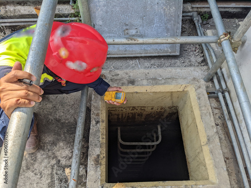 Worker and safety officer take data for gas test before confine space activity. The photo is suitable to use for industrial background and construction content media.