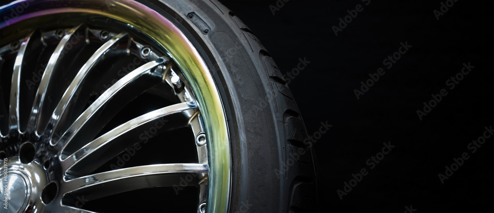 A detail of a fashionable expensive chrome ring with a colored rim on an empty black background. A layout for advertising copy space tires discs or a spare parts store or car service.