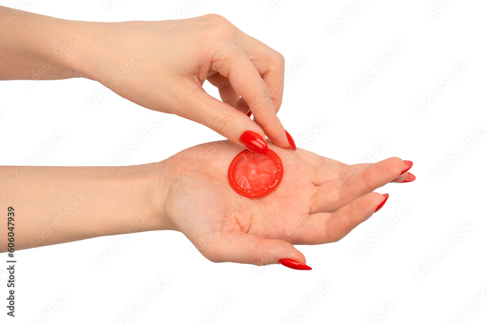 A red condom in a woman hand with red nails isolated on white background. A red condom in a woman hand with red nails isolated on white background.