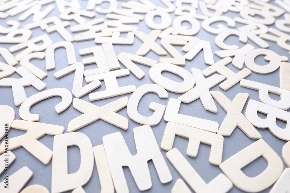 Scattered wooden white alphabets on gray background, English letters for learning English concept, glossary, words, and vocabulary Scattered wooden white alphabets on gray background, English letters for learning English concept, glossary, words, and vocabulary
