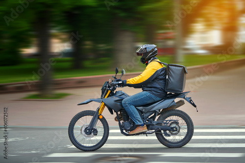 Food delivery motor bike driver with backpack behind back is on his way to deliver food. Courier on motorcycle delivering food. MOTION BLUR. Shipping of goods to customers from restaurant. Takeaway