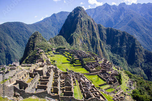 Incan Machu Picchu citadel wide panoramic view from summit, mountains and blue sky in background