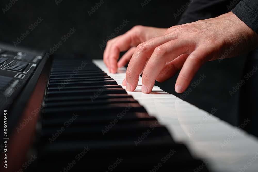 Playing a synthesizer on a dark background. The musician plays the synthesizer.