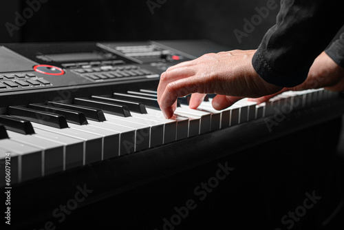 Playing a synthesizer on a dark background. The musician plays the synthesizer.