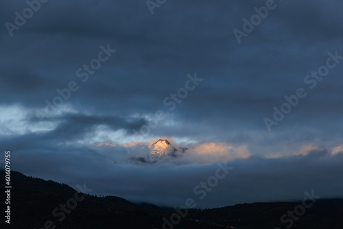 Fotografie A scenics view of majestic snowy mountain summit engulfed in white altitude clou