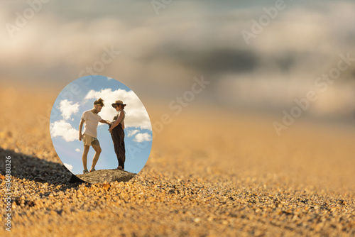 pareja, embarazada reflejada en un espejo en la playa con el mar arena y de fondo al tardecer photo