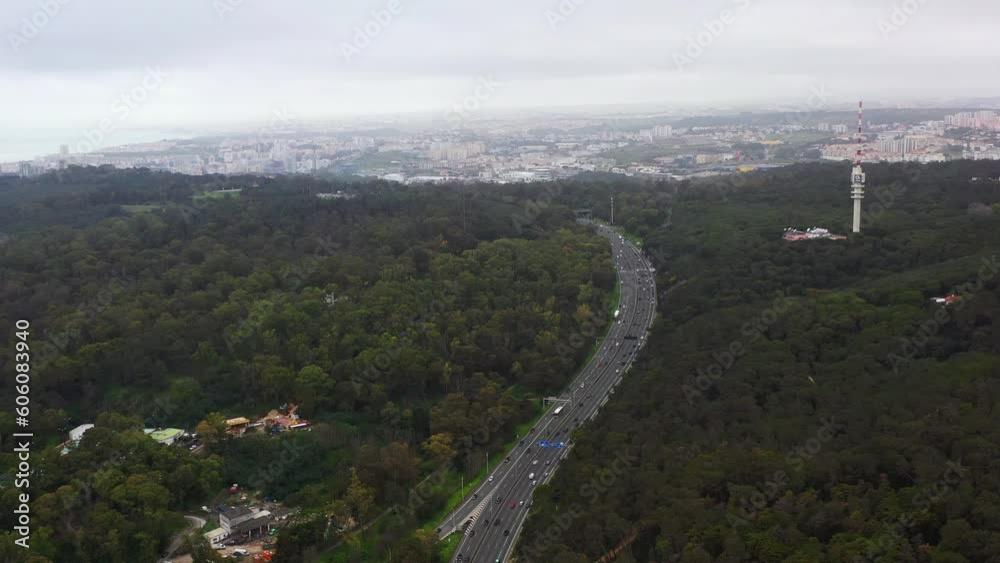 Highway through forest with pine trees in autumn, aerial view. Road with forrest trees and car. Forest road for transpotrs. Aerial above view of freeway. Asphalt road in Monsanto park in Lisbon Highway through forest with pine trees in autumn, aerial view. Road with forrest trees and car. Forest road for transpotrs. Aerial above view of freeway. Asphalt road in Monsanto park in Lisbon