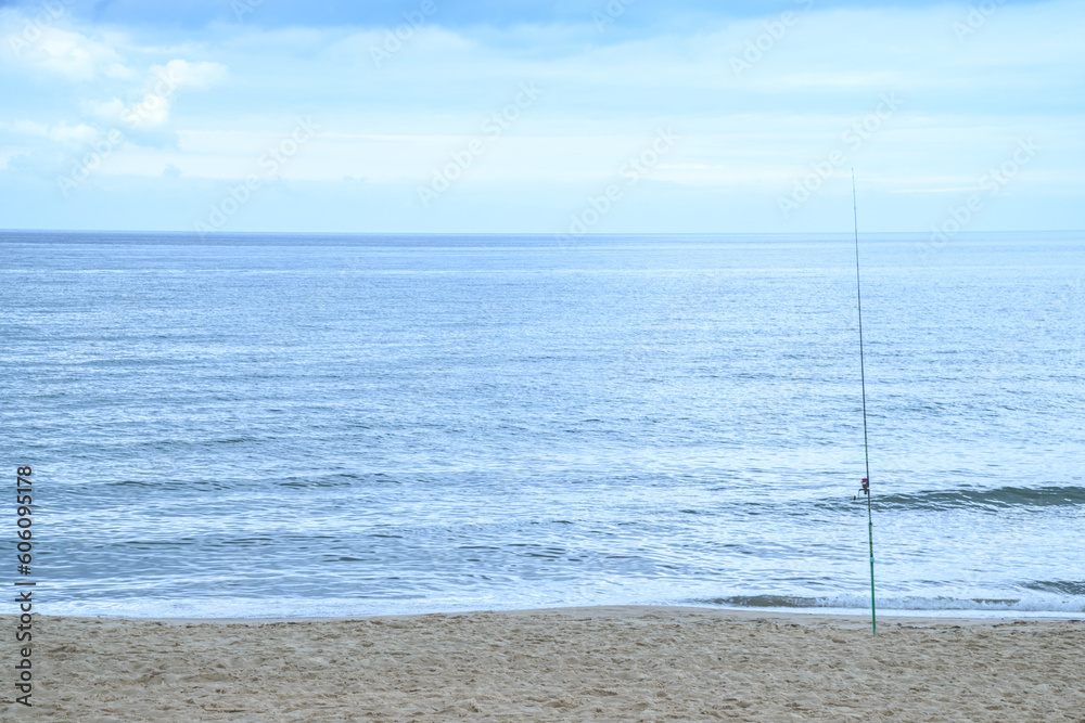 Image of fishing rod with beach panorama and sea in horizon Image of fishing rod with beach panorama and sea in horizon