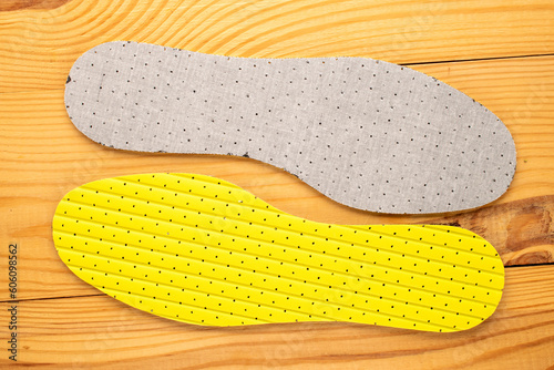 One pair of latex insoles on a wooden table, top view.