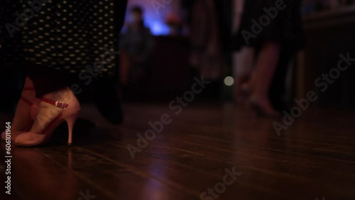foot steps in the floor of a milonga dancing party, peopler dancing Argentine Tango in a moody bar cafe