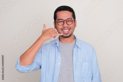 Adult Asian man smiling happy while give call me hand sign photo