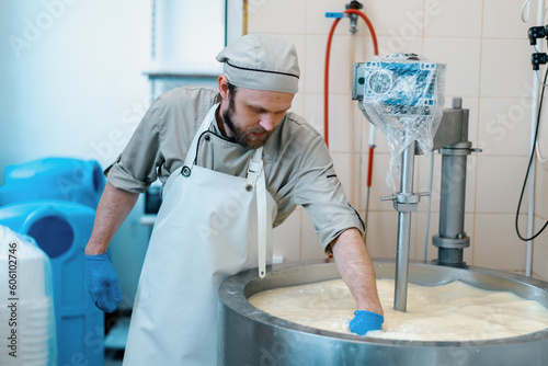 Tablou pe pânză milk mixing at cheese factory cheese maker checks cheese by hand in large tank P