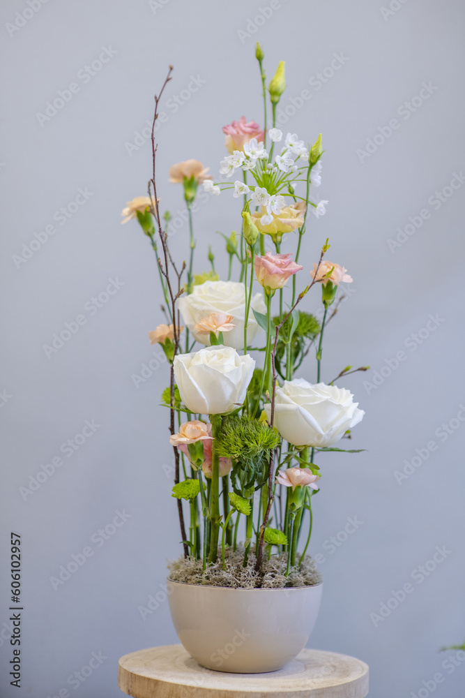 Vertically constructed composition of flowers in pots. Floral arrangement with white roses