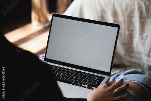 Woman Interacting with MacBook in a lap, browsing computer with blank screen mock-up for your design at home office with blurry background with free space for custom text about business
