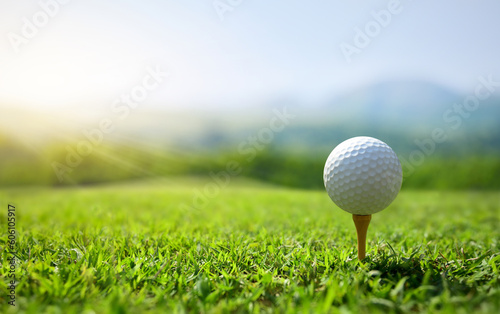 Golf ball on tee with sunrise background.