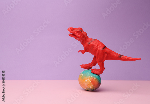 Toy tyrannosaurus rex is balancing on colored easter egg. Minimal easter still life